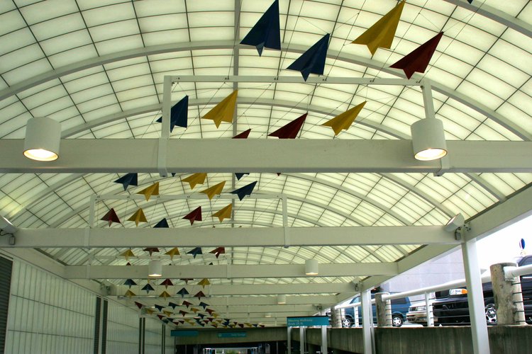 Colorful powder coat painted aluminum airplanes flock in a curve along the ceiling.