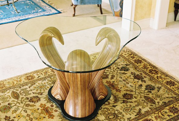 The three laminiated wood sculptures curve up and in to support the glass table top.