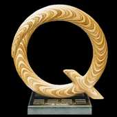 Laminated wood sculpture in the shape of the letter "Q".
