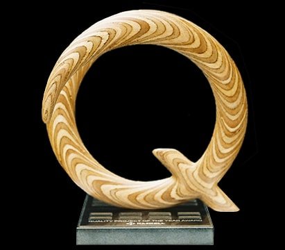 Laminated wood sculpture in the shape of the letter "Q".