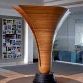 A large, fluted laminated wood sculpture that is split down the middle.
