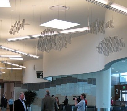 Expanded aluminum mesh fish hang from the ceiling among the hanging lights.