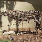 Lifesize stylized stick horse behind a fence at the zoo.