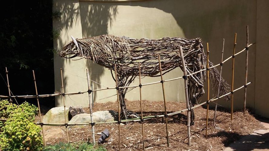 Lifesize stylized stick horse behind a fence at the zoo.