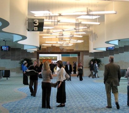 Expanded aluminum mesh fish hang from the ceiling above the airport visitors.