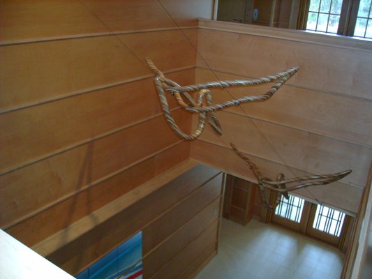 The laminated wood pelican sculptures are suspended from wires.