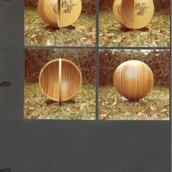 Laminated wood sculpture that is half of a hollow sphere with a narrow arch with printed words: "Salute to the Arts."