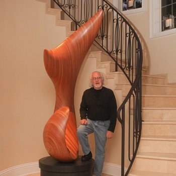 David Engdahl stands next to the tall laminated wood sculpture.