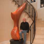 David Engdahl stands next to the tall laminated wood sculpture.