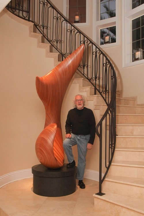 David Engdahl stands next to the tall laminated wood sculpture.
