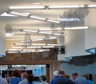 Expanded aluminum mesh fish hang from the ceiling among the hanging lights.